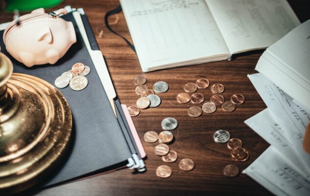 coins scattered on desk with papers and creative pig wallet