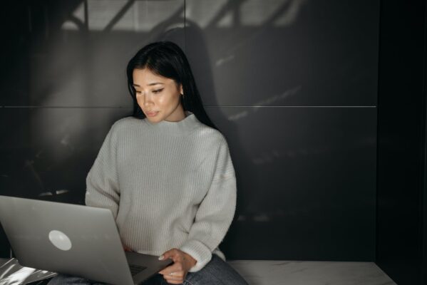 woman in white sweater using laptop